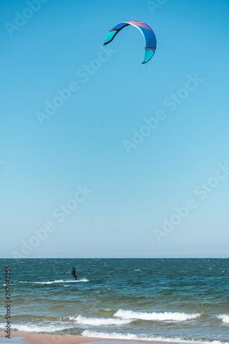 Wide shot of kitesurfer swimming on an ocean or sea near beach. Summer color grading. Vertical orientation. 