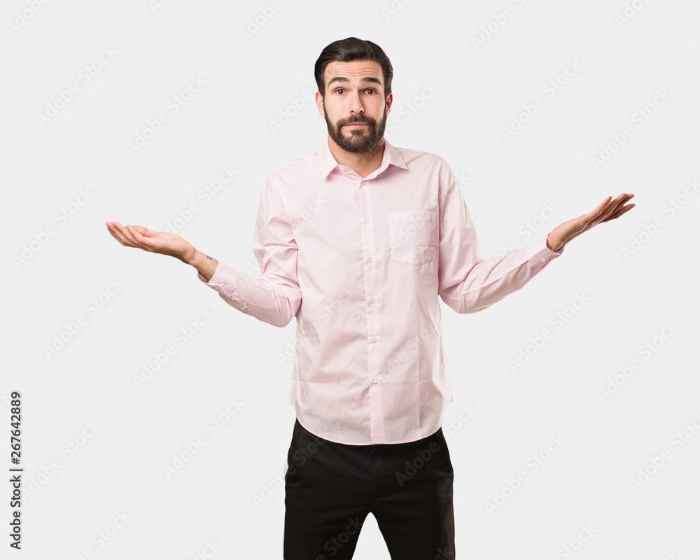 Young handsome man doubting and shrugging shoulders Young handsome man doubting and shrugging shoulders