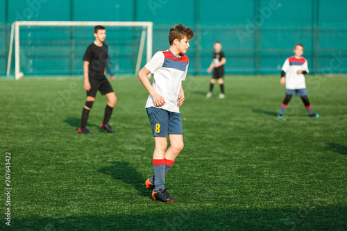 Football teams boys in yellow white sportswear play soccer on the green field. Dribbling skills. © Natali