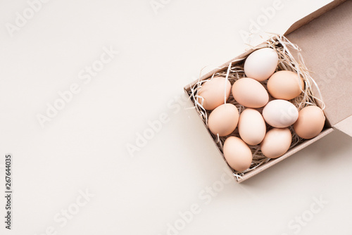 Closeup Raw fresh organic farm chicken eggs, brown color, in craft box on a light background  , banner, Flat lay. Natural eco Happy Easter card.