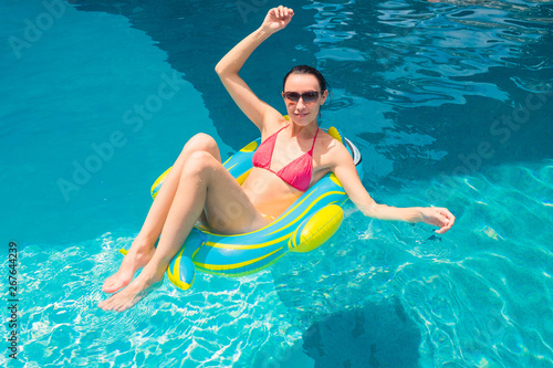 A young girl is swimming and relaxing in a blue pool.