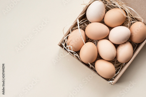 Closeup Raw fresh organic farm chicken eggs, brown color, in craft box on a light background , banner, Flat lay. Natural eco Happy Easter card.