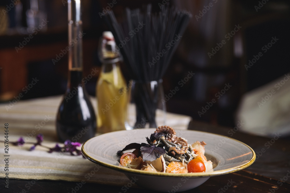 black spaghetti with octopus, shrimp, cherry tomatoes and basil