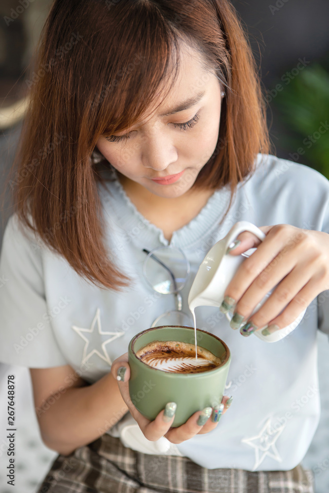 Young Asian woman barista making a latte art in a cup of Cappuccino Coffee Young Asian woman barista making a latte art in a cup of Cappuccino Coffee