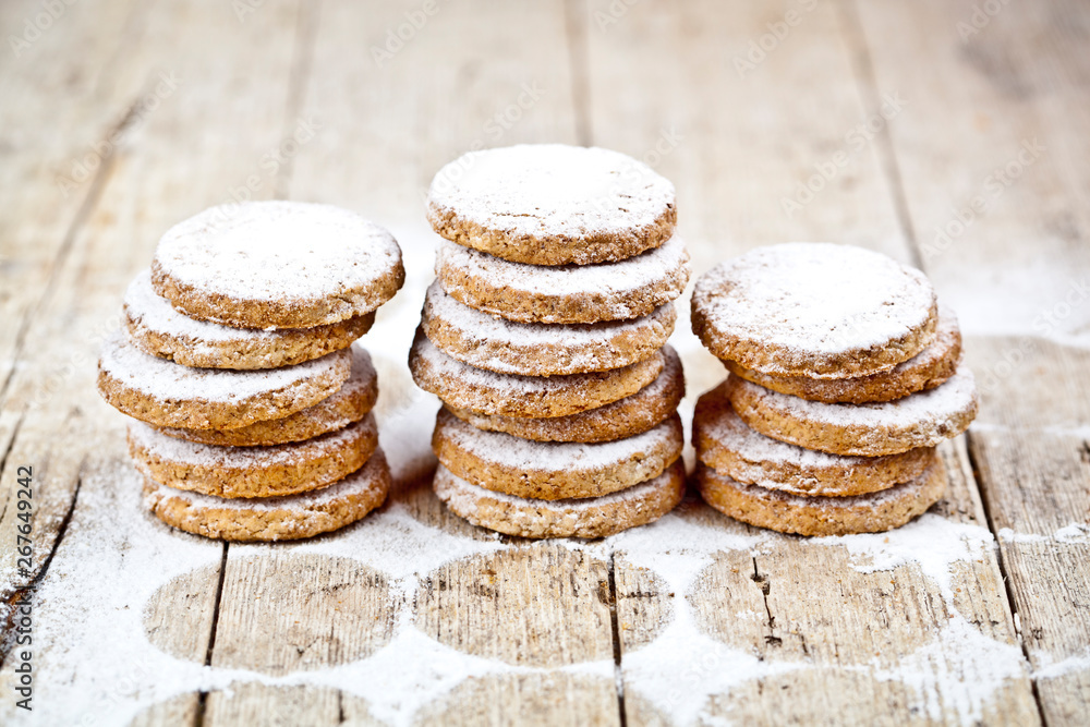 Fresh oat cookies stacks with sugar powder on rustic wooden table. Fresh oat cookies stacks with sugar powder on rustic wooden table.