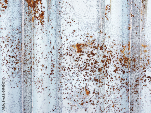 Fog and texture corrugated sheet of iron with rust appearing through the white paint..