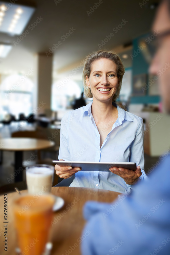 Smiling woman and man with tablet in a cafe Smiling woman and man with tablet in a cafe