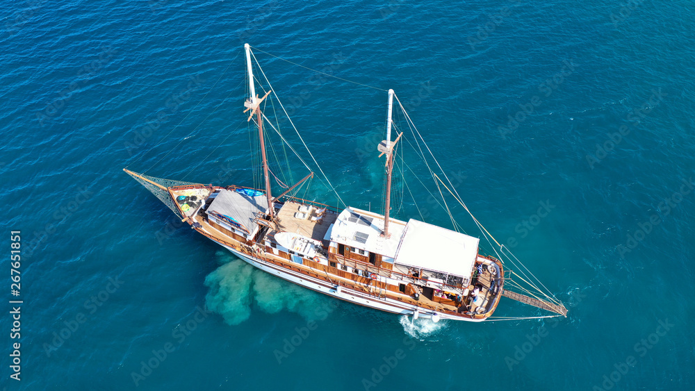 Aerial birds eye drone view of beautiful wooden sailboat in deep blue sea of island of Mykonos, Cyclades, Greece