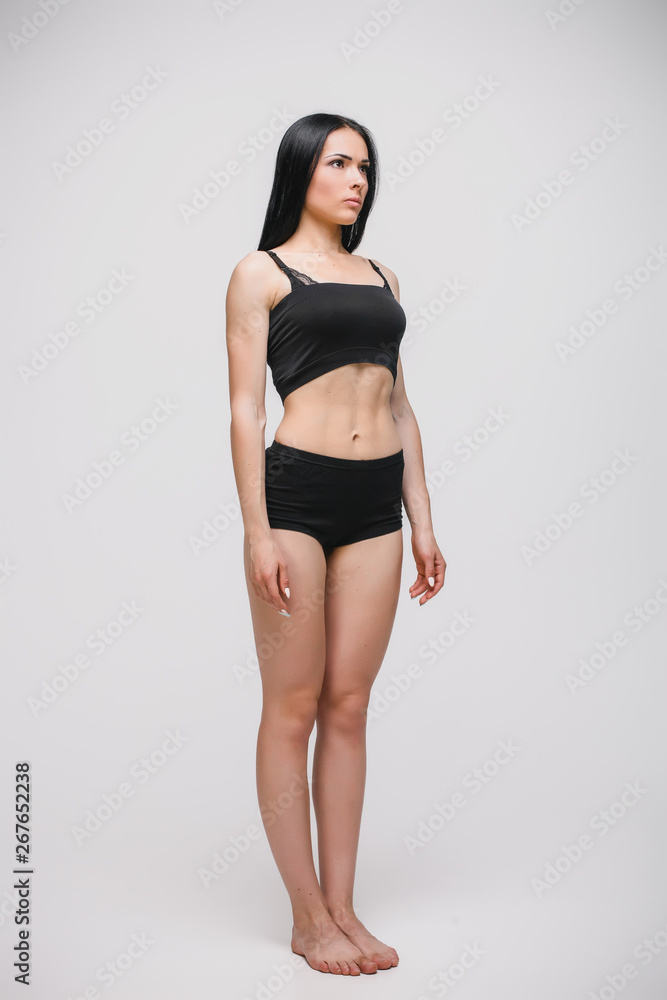 Obraz premium serious young model in black underwear standing on gray studio background. full length photo
