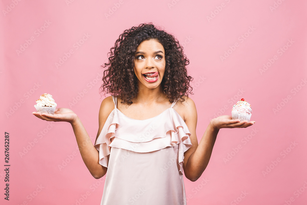 Black american african happy woman with curly afro hair style making a mess eating a huge fancy dessert over pink background. Eating cupcake. Black american african happy woman with curly afro hair style making a mess eating a huge fancy dessert over pink background. Eating cupcake.