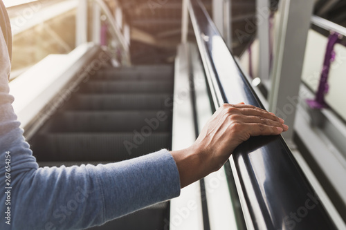 Canvas Print Woman's right hand on the escalator handrail on the train station