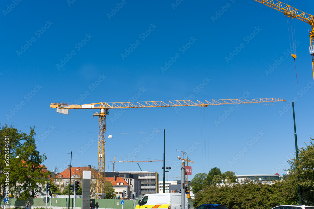 Two cranes working on a construction site with clear blue sky