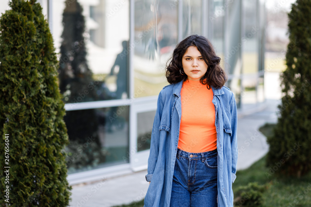 Young pretty girl walking on the street, dressed in jeans and denim shirt. Student weekdays