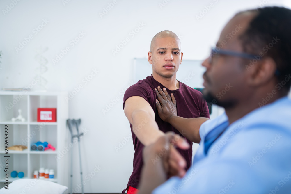 Fototapeta premium Young bodybuilder feeling worried having physical examination