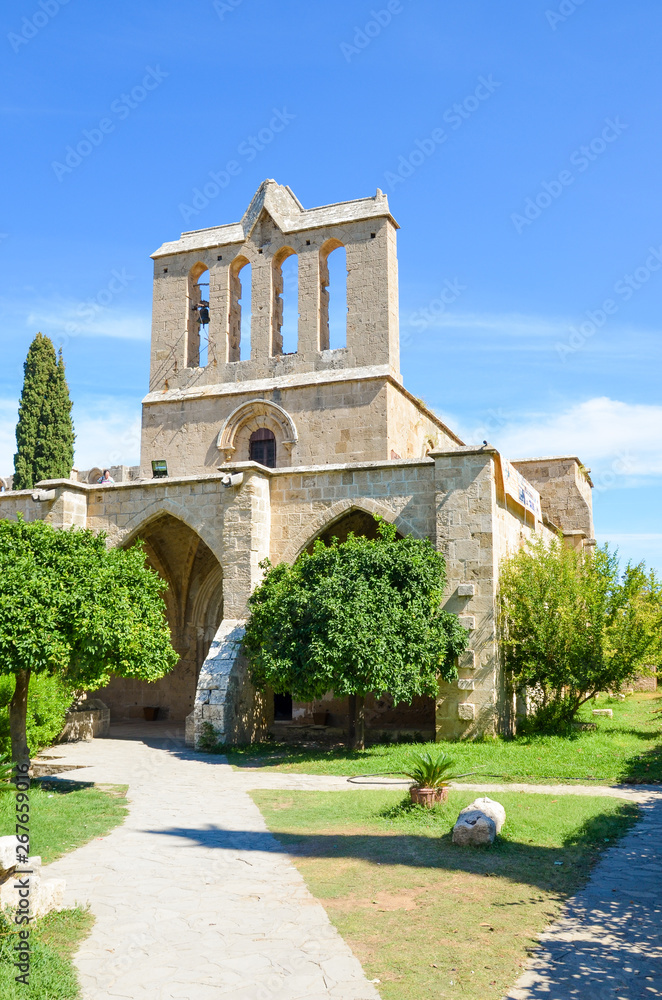 Vertical photo of beautiful Bellapais Abbey in Northern Cyprus taken with blue sky above. The ancient monastery is one of the most popular Cypriot tourist attractions