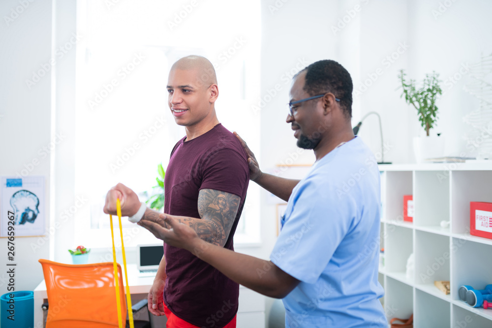 Fototapeta premium Sportsman with big tattoo on arm doing exercises visiting therapist