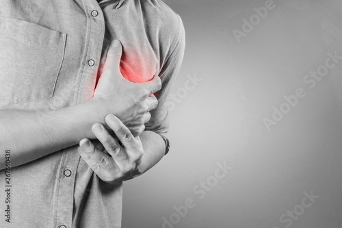 Fotografia Man having a sudden heart attack on gray background