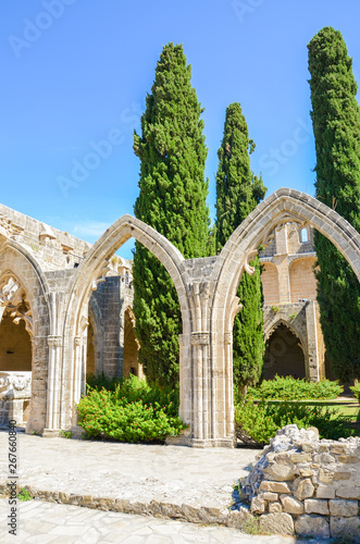 Vertical photography of the inner courtyard with typical arches in Bellapais Abbey in Turkish Northern Cyprus. The historical monastery is a popular tourist attraction. Captured with blue sky