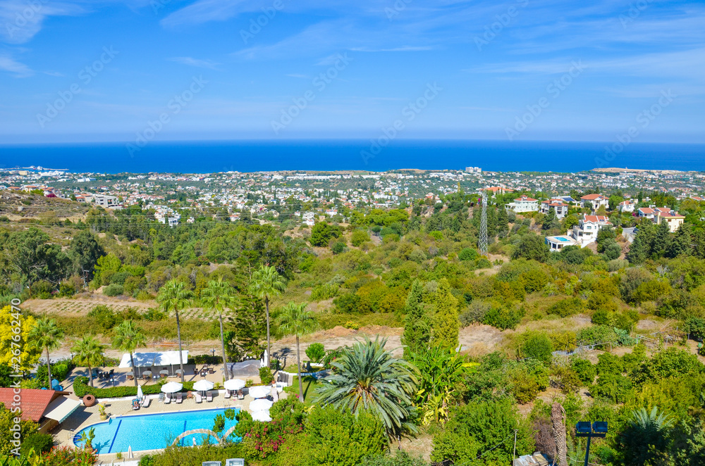 Amazing view of subtropical landscape in Cypriot Kyrenia region taken in summer season. The countryside buildings surrounded by green trees are overlooking the Mediterranean sea