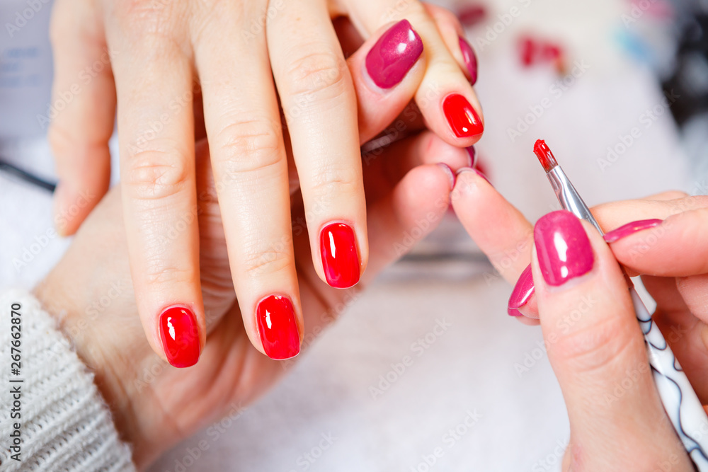 Manicure in progress - Beautiful manicured woman's nails with red nail polish. The industry of beauty and nail care, beauty salons Manicure in progress - Beautiful manicured woman's nails with red nail polish. The industry of beauty and nail care, beauty salons