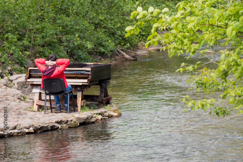 man in red jacket relax piano on river photo