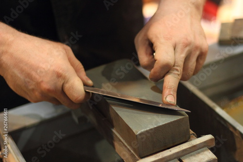Manual sharpening blade of knife on a grinding stone photo