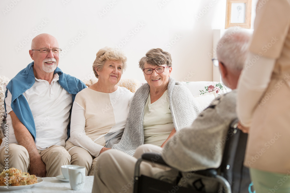 Fototapeta premium Group of senior friends sitting together in common living room of nursing home