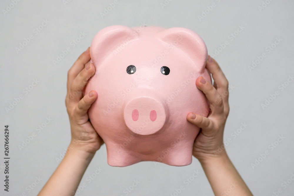 Little kid holding piggy bank, closeup. Piggy bank in hand. Money savings concept