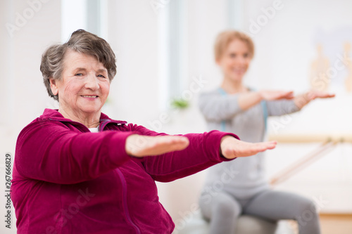 Smiling elderly lady holding her arms during pilates for seniors