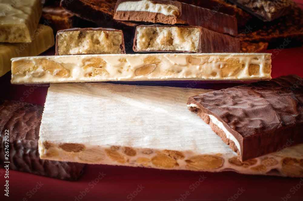 Turron. Festive sweets. Warm sunlight. Selective focus. Blurred background. Traditional Spanish Christmas candy. Torrone and nougat with nuts. Texture, layers. Turron. Festive sweets. Warm sunlight. Selective focus. Blurred background. Traditional Spanish Christmas candy. Torrone and nougat with nuts. Texture, layers.