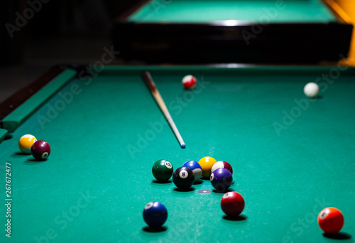 Billiard balls on green table with billiard cue