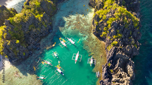 Fototapeta Naklejka Na Ścianę i Meble -  Aerial drone view of kayaks inside a beautiful shallow tropical lagoon surrounded by jagged cliffs and jungle Small Lagoon, El Nido