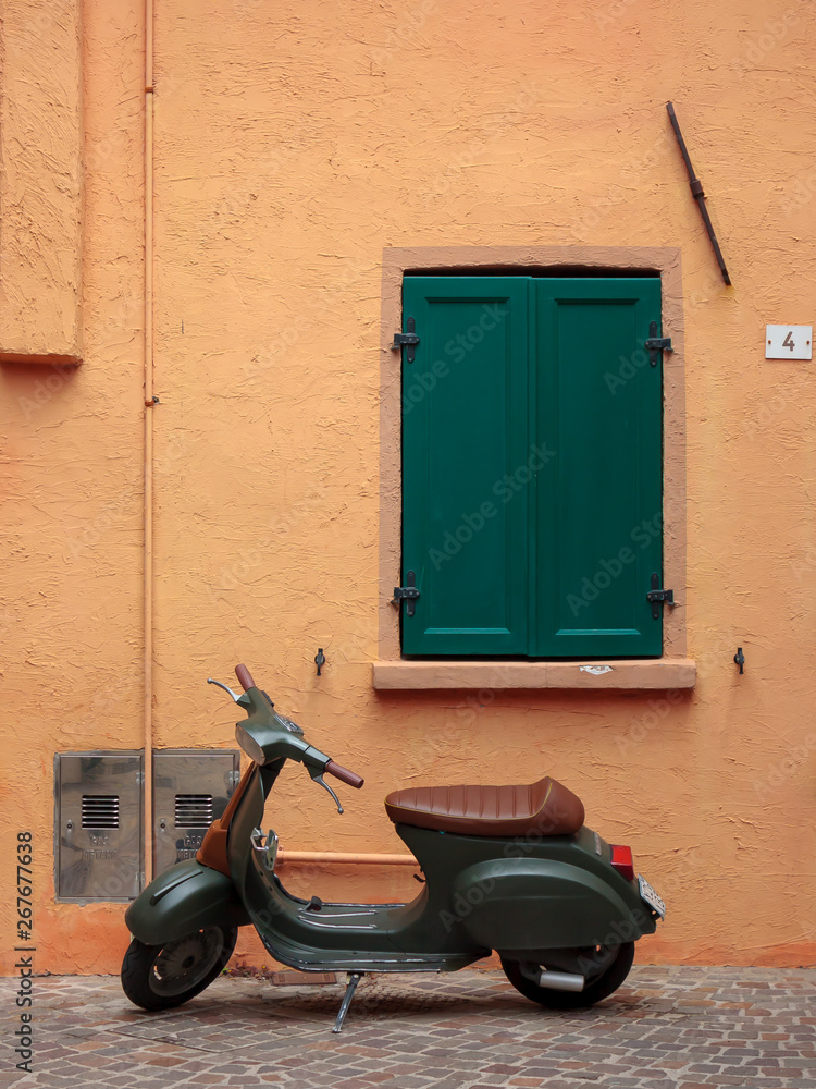 an old Italian scooter parked in front of a colorful house