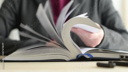 Businesswoman reading book at office desk, searching for the business related information and flipping pages in slow motion photo