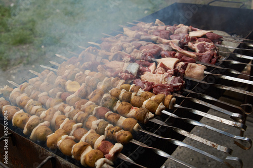 Preparation of shish kebab on skewers, close-up. BBQ grill with lamb meat and potatoes
