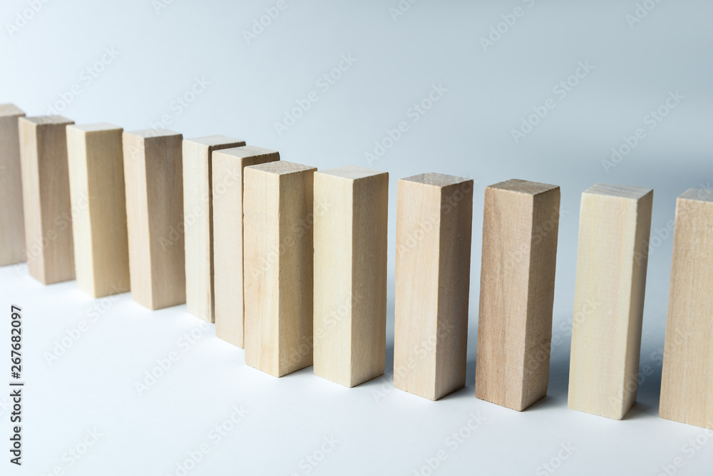 A long curved line of wooden cubes, as a symbol of a queue, competition for a position or team, on a uneven white background. Horizontal frame A long curved line of wooden cubes, as a symbol of a queue, competition for a position or team, on a uneven white background. Horizontal frame