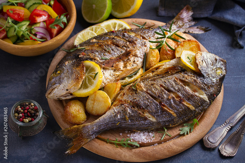 Roasted fish and potatoes, served on wooden tray - image
