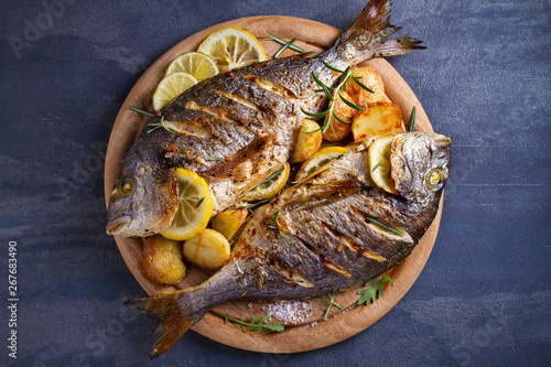 Roasted fish and potatoes, served on wooden tray. overhead, horizontal - image