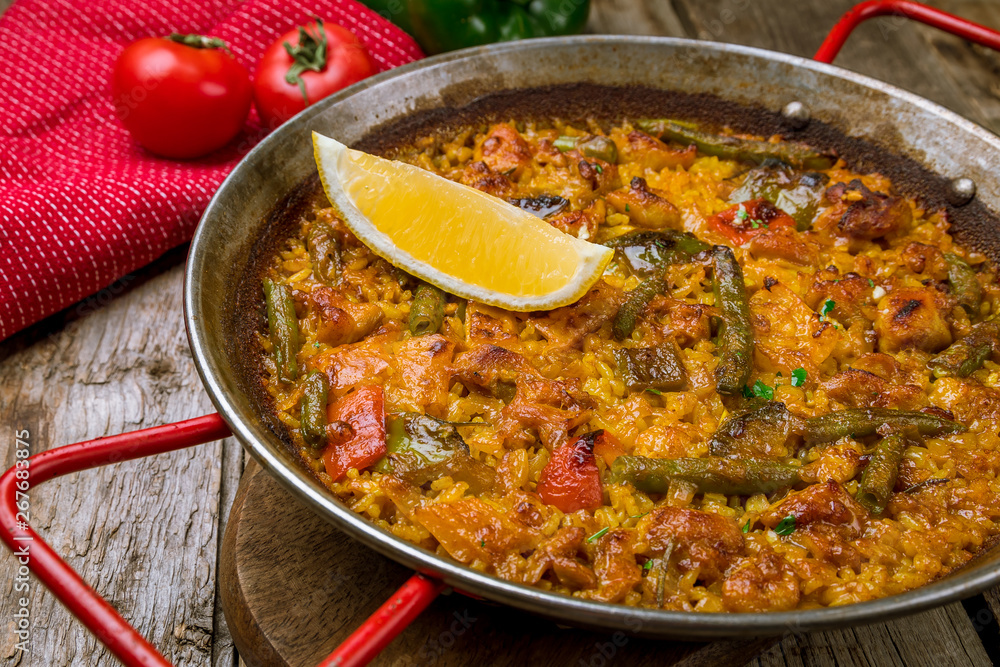 paella with chicken on wooden background