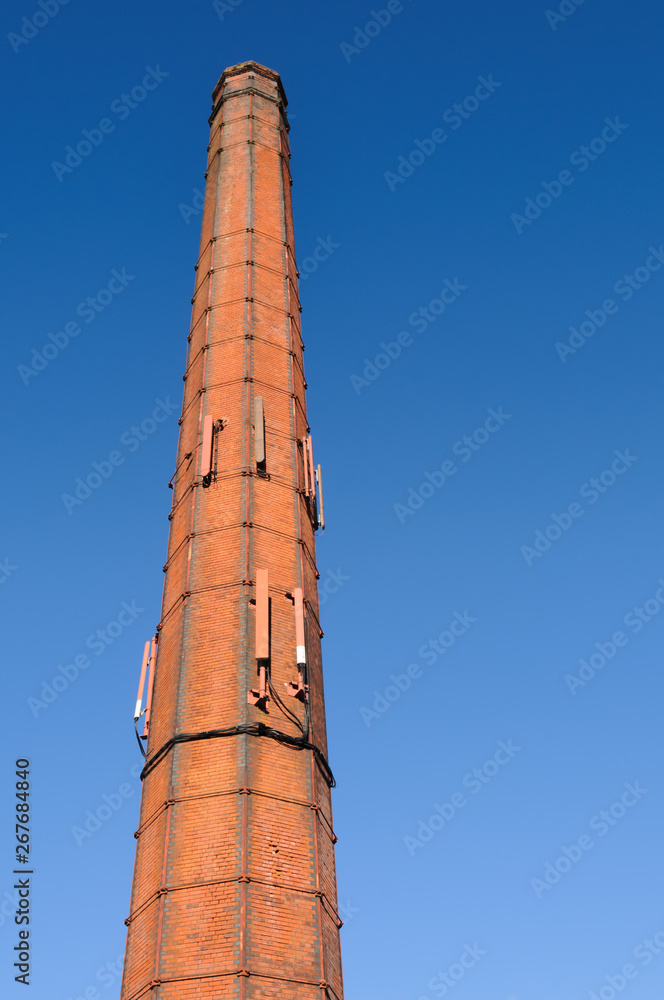 Tall red-brick chimney, common at 19th Century Irish linen mills, with mobile phone antennas Tall red-brick chimney, common at 19th Century Irish linen mills, with mobile phone antennas