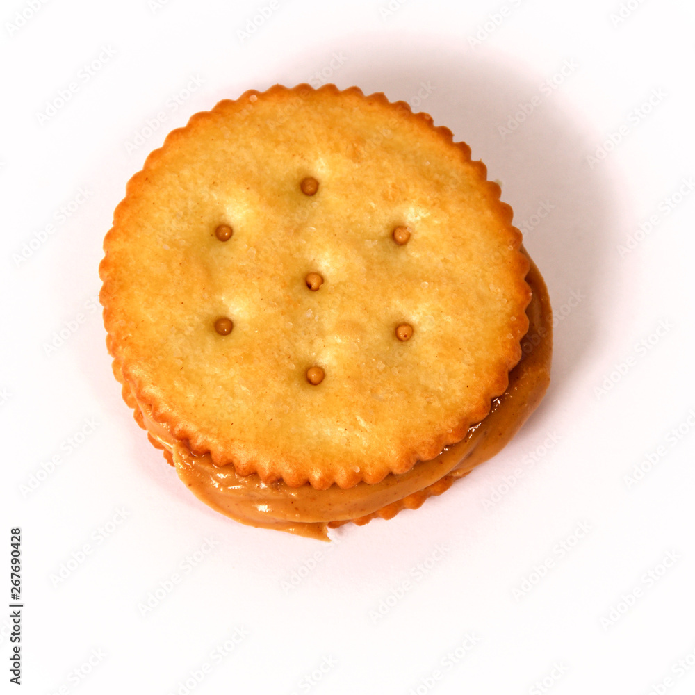 Natural organic peanut butter fills and oozes out of this sandwich made with golden round crackers on white background from above Natural organic peanut butter fills and oozes out of this sandwich made with golden round crackers on white background from above