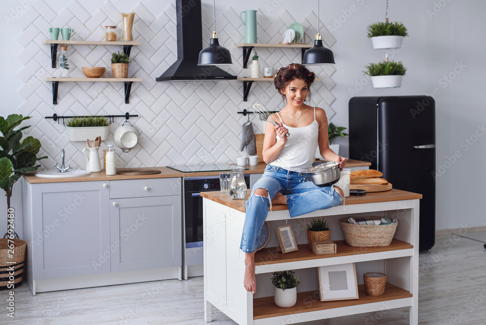 Pretty woman in casual clothes having fun while preparing dough at stylish kitchen. Young pretty woman baking on bright home kitchen. Pretty woman in casual clothes having fun while preparing dough at stylish kitchen. Young pretty woman baking on bright home kitchen.