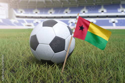 Guinea-Bissau flag in stadium field with soccer football