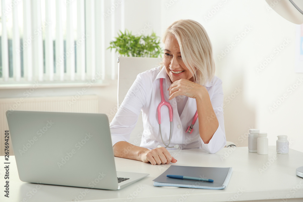 Doctor consulting patient using video chat on laptop in clinic Doctor consulting patient using video chat on laptop in clinic