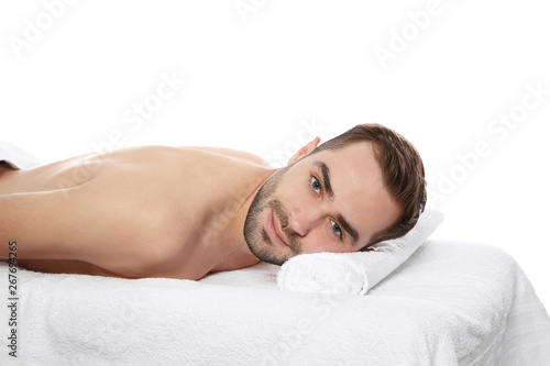 Handsome man relaxing on massage table against white background. Spa service