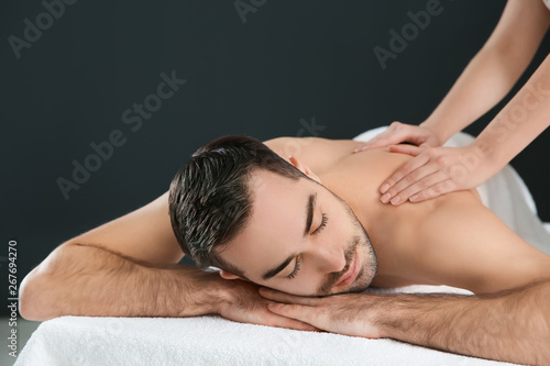 Handsome man receiving back massage on black background. Spa service