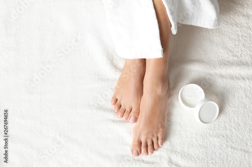 Photos Top view of woman with beautiful feet and moisturizing cream on white towel, space for text