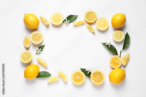 Fotografie Frame made of lemons, leaves and flowers on white background, top view with space for text