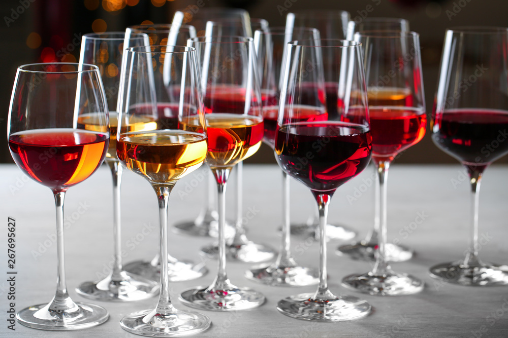 Group of glasses with different wines on table against blurred background