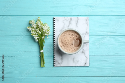 Flat lay composition with notebook, lily of the valley bouquet and coffee on wooden background